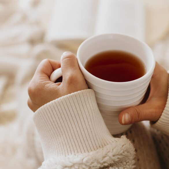 young-woman-holding-cup-tea-while-enjoying-winter-holidays