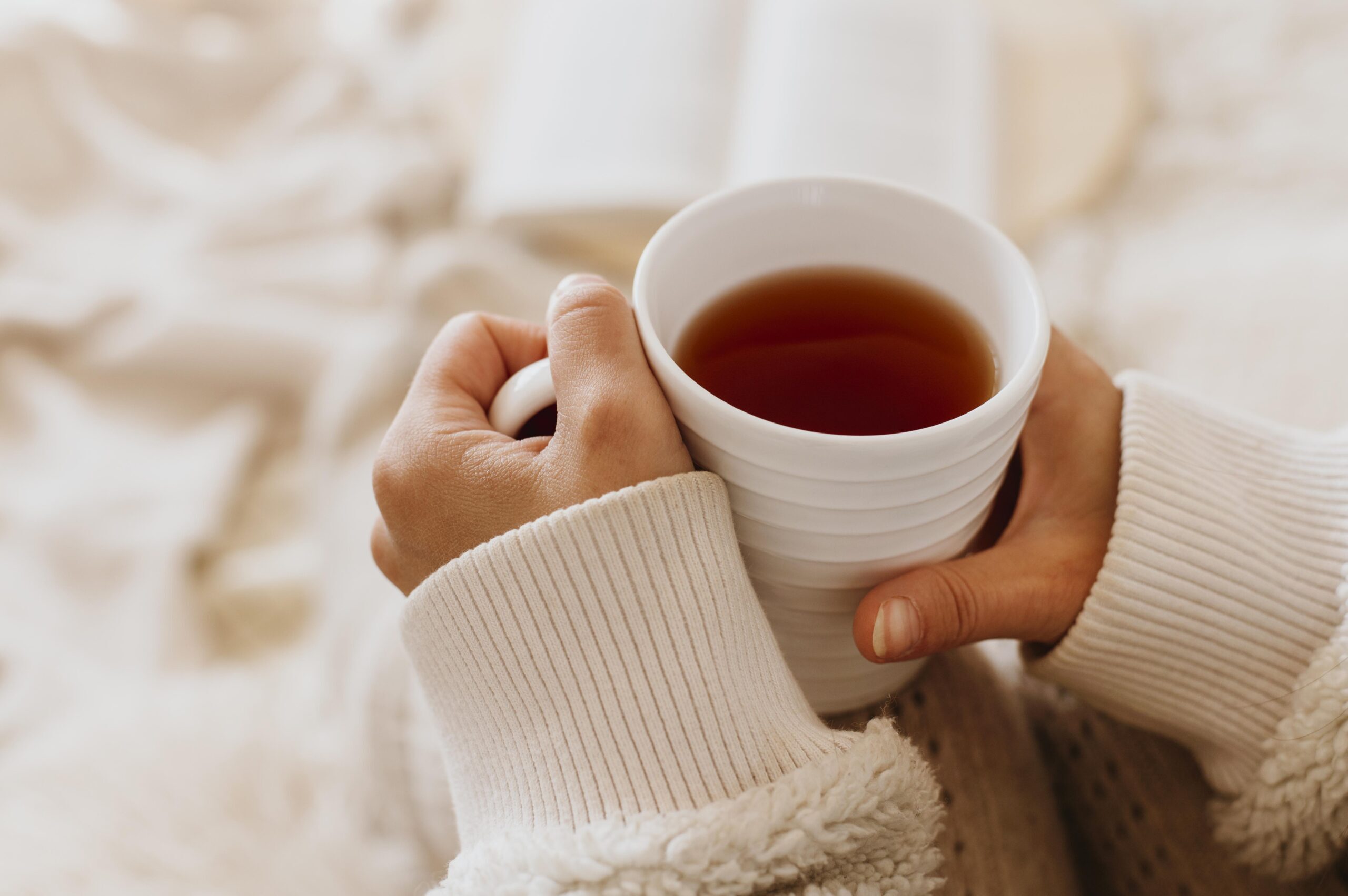 young-woman-holding-cup-tea-while-enjoying-winter-holidays